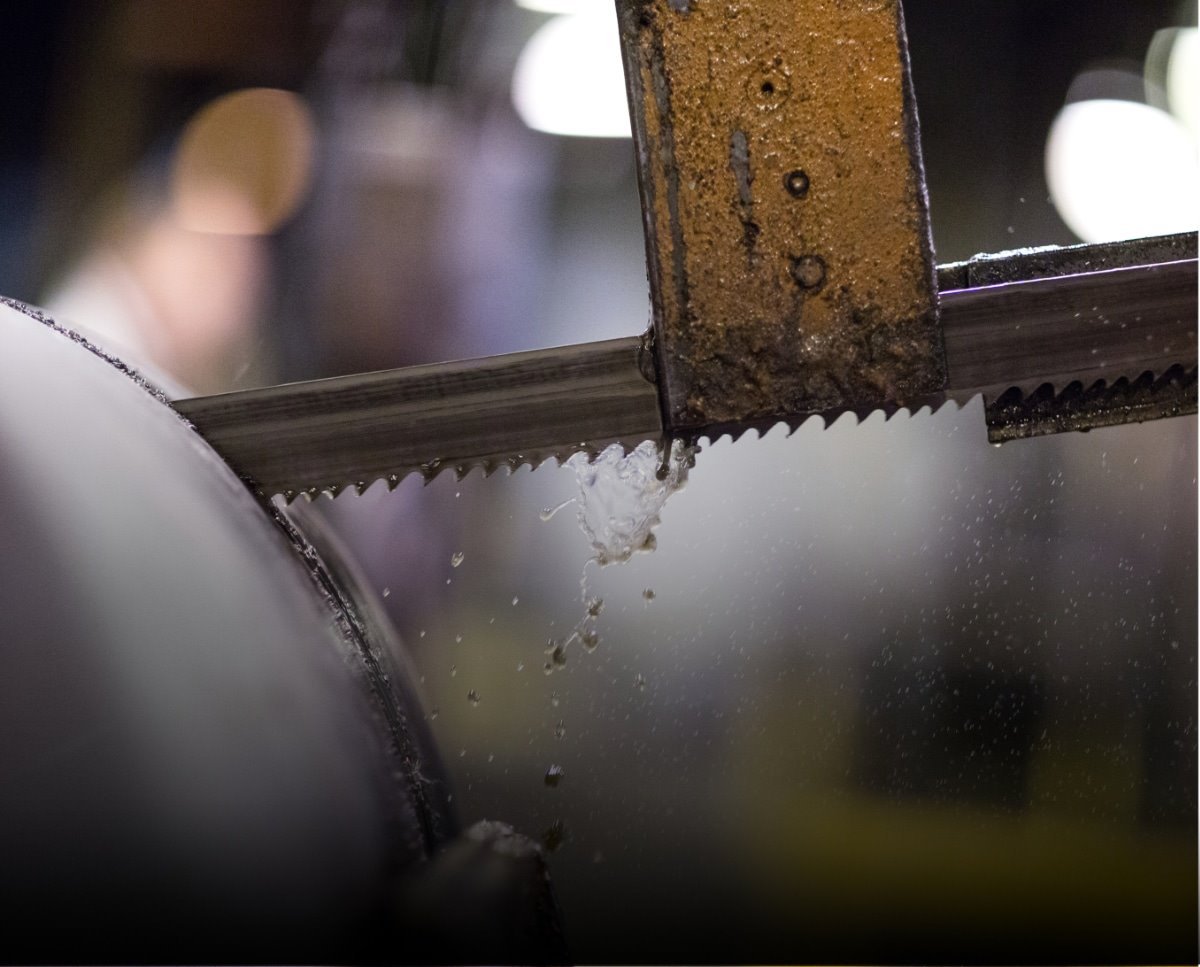 An industrial saw blade slicing through a piece of Dura-Bar
