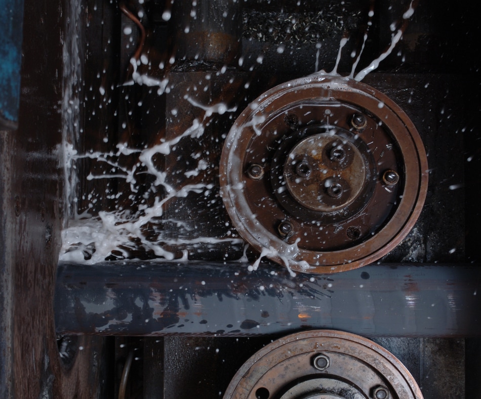 An iron rod being drilled with industrial machinery